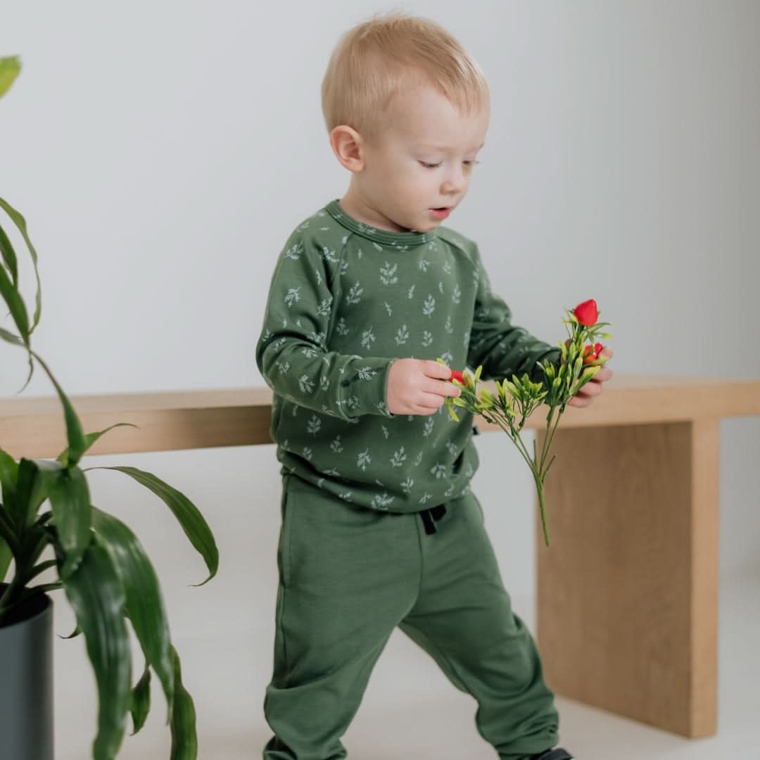 Toddler in bamboo leaf-patterned outfit holding flowers for newborn apparel in Canada