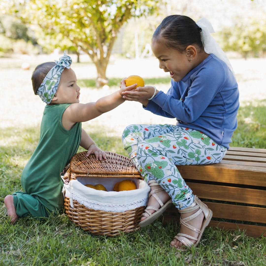 Two children play with an orange, showcasing Youth Bamboo Leggings from top baby clothes Canada