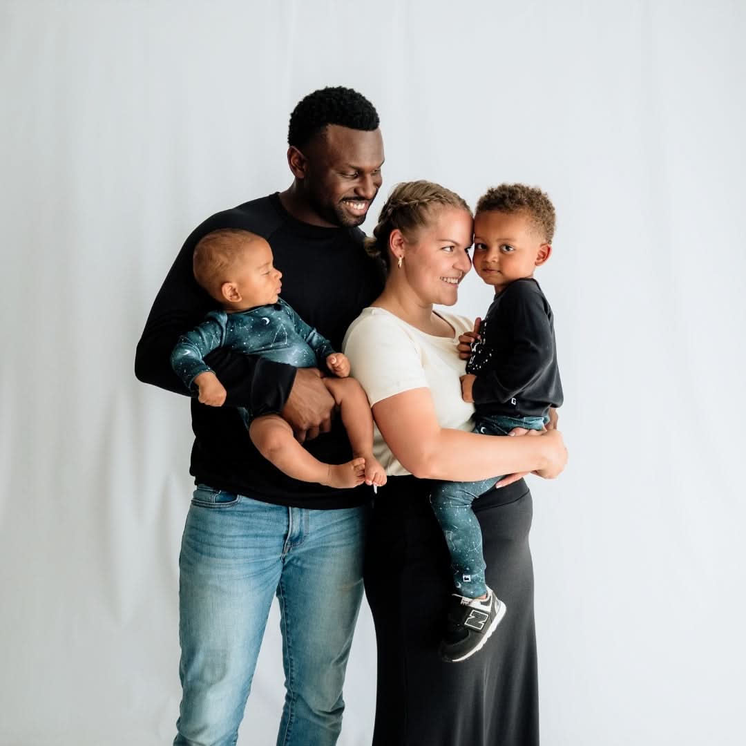 A man and woman, each holding a young child in a Little & Lively Bamboo Baby Long-Sleeved Onesie, stand close together and smile against a plain white background.