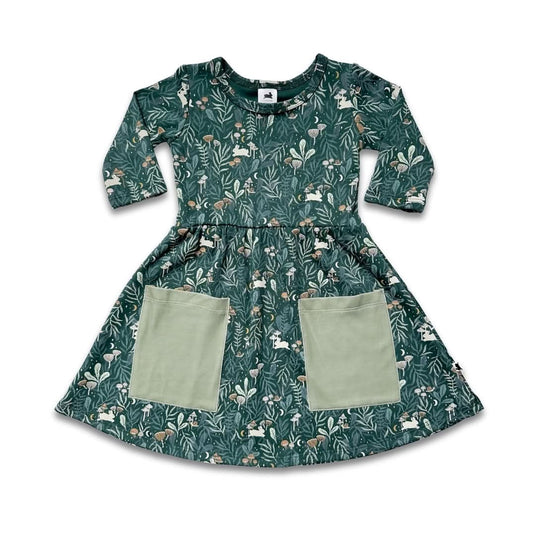 The Little & Lively Baby/Kids Bamboo Clementine Dress features 3/4 sleeves, green bamboo fabric, an all-over forest and animal print, and two large light green front pockets. Shown on a white background.