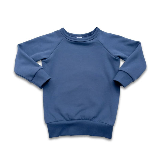 The Little & Lively Youth Bamboo Fleece Raglan Pullover, shown in solid blue, features ribbed cuffs, collar, and waistband. Ethically made for comfort, it's laid flat on a white background displaying the crewneck and long-sleeved design.
