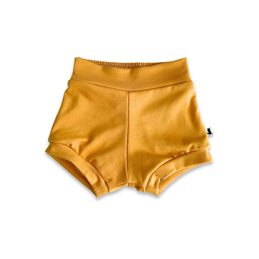 The Little & Lively Baby Bamboo High-Waisted Shorties — Last Call feature a wide waistband and folded leg cuffs in mustard yellow, shown against a white background.