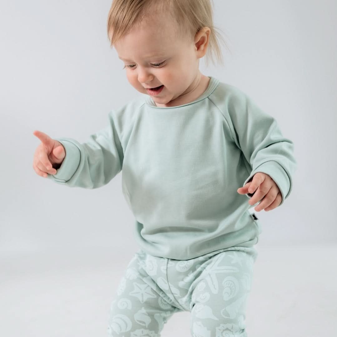 Child wearing a light green outfit with a plain background