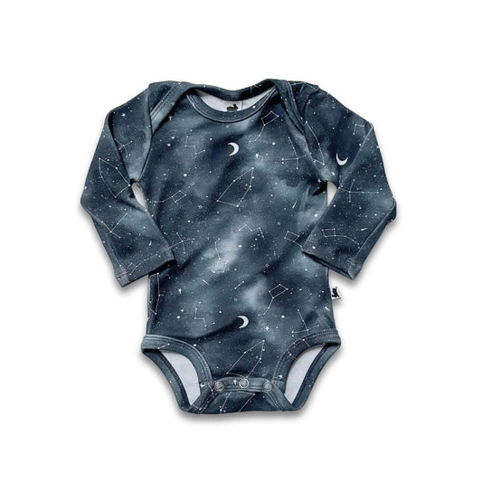 The Little & Lively Bamboo Baby Long-Sleeved Onesie features a dark blue night sky print with stars, constellations, and crescent moons, made from soft bamboo fabric and shown laid flat on a white background.
