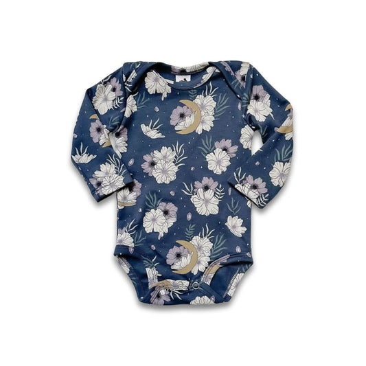 The Little & Lively Bamboo Baby Long-Sleeved Onesie features a navy background with white, pink, and beige floral and moon prints. Made from soft bamboo fabric, it offers easy snap closures at the bottom.