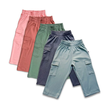 Five pairs of Little & Lively Youth Bamboo Cargo Pants in pink, rust, green, blue, and teal are displayed fan-shaped on white. Each has an adjustable drawstring waist, elastic waistband, and side cargo pockets.